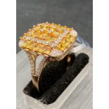 A 9ct gold fashion ring in a cocktail style with yellow and clear stones. Size S1/2