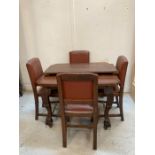 An oak extendable dining table on carved legs with castors and four brown leather upholstered dining
