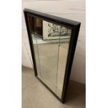 A panelled wall mirror with brass studs in a black gilt frame (80cm x 130cm)