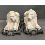 A pair of plaster recumbent lions on metal stand