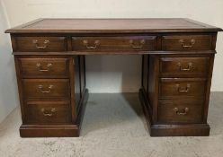 An oak pedestal desk with red leather top and brass drop handles (H78cm W136cm D76cm)
