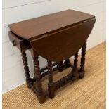 An oak gate leg table with drawer to centre