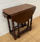 An oak gate leg table with drawer to centre