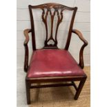 An early 19th Century mahogany arm chair with pierced splat back over dropping leather seat