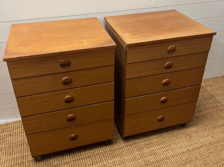 A pair of Schreiber five drawer bedside table on castors (H71cm W50cm D43cm)
