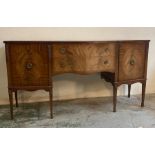 A mahogany serpentine fronted sideboard, two drawers flanked by cupboards and ornate floral carving