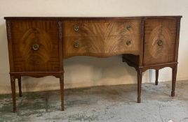 A mahogany serpentine fronted sideboard, two drawers flanked by cupboards and ornate floral carving