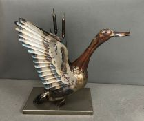 A metal sculpture of a duck taking flight