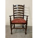An oak spool turned ladder back arm chair upholstered in red