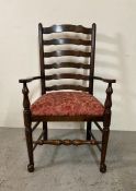 An oak spool turned ladder back arm chair upholstered in red