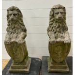A pair of reclaimed garden lion statues holding shields on pier caps