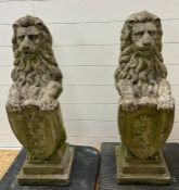 A pair of reclaimed garden lion statues holding shields on pier caps