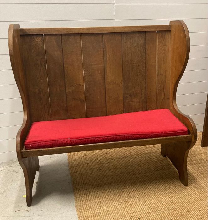 An oak vintage two seater settle with red upholstered cushions (H123cm W122cm Seat Depth 39cm)