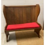 An oak vintage two seater settle with red upholstered cushions (H123cm W122cm Seat Depth 39cm)