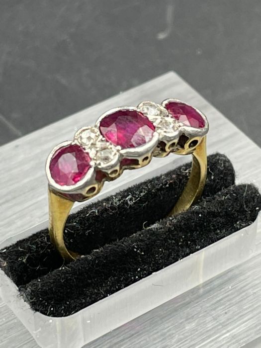 An Antique three stone ruby ring with four small diamonds. Size K