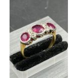 An Antique three stone ruby ring with four small diamonds. Size K