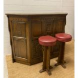 An oak carved Arts and Crafts style bar with Palace of Westminster motif and two stools (H107cm