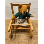 A vintage child's walker chair along with a teddy bear