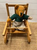 A vintage child's walker chair along with a teddy bear