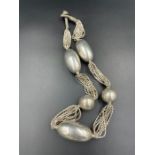 A large silver antique necklace with large silver balls.