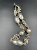 A large silver antique necklace with large silver balls.