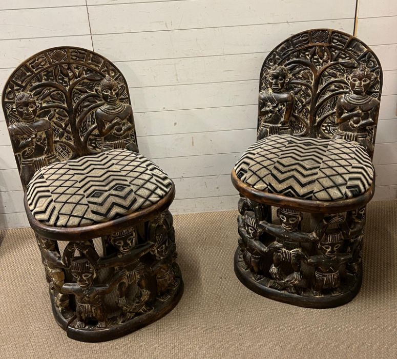 A pair of carved seats with tribal theme carving to back and base