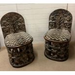 A pair of carved seats with tribal theme carving to back and base