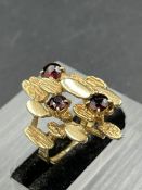 A vintage abstract ring, designed as three round cut garnets, weighing an estimated 0.28, 0.24 and