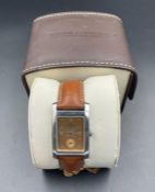 A Baume & Mercier gents wristwatch, comprising a steel rectangular case, bronzed dial with dot and