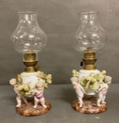 Two hand painted oil lamps with cherub motif in the Dresden manner