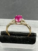 A ruby and diamond ring, oval cut ruby weighing a calculated, with ten round cut diamonds set to the