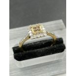 A 9ct gold fashion ring with central yellow stone surrounded by white stones and shoulders (