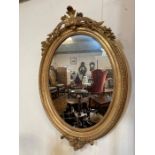 A gilt oval mirror with scrolling foliage to frame (H105cm W75cm)