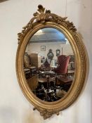 A gilt oval mirror with scrolling foliage to frame (H105cm W75cm)