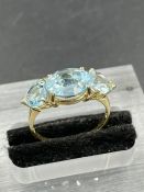 A three stone blue topaz ring with a central oval cut topaz weighing an estimated 3.00ct with a