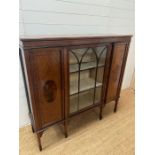 A display cabinet with gazed door to centre flank by two panelled doors on tapering legs with