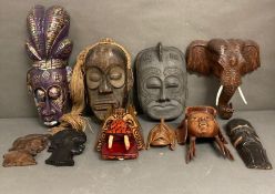A selection of wall hanging tribal masks and carvings