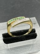 An emerald and cubic zirconia yellow metal half eternity ring. Grain set with a row of eight round