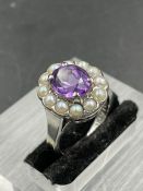 An amethyst ring with central stone surrounded by twelve seed pearls on a 18ct white gold and