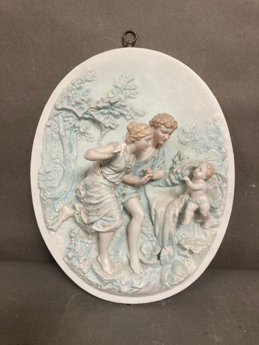 A porcelain bisque wall plaque of a courting couple and a cherub