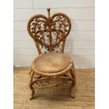 A cane and wicker side chair with the back rest in the form of a heart