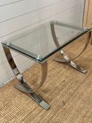 A glass and chrome cross legged side table (H50cm W67cm D47cm)