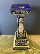 A large glazed pedestal or jardinière stand on blue grounds with cherub decoration to pillar.