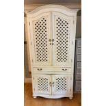 A white painted cupboard with lattice work to doors and centre drawers (H220cm W106cm D67cm)