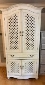 A white painted cupboard with lattice work to doors and centre drawers (H220cm W106cm D67cm)