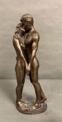 A bronze effect sculpture titled "The Kiss" by Brian Collins