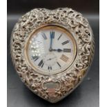 An 1899 heart shaped silver pocket watch stand on easel back with overlarge pocket watch.