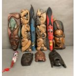 A selection of wall hanging tribal masks and carvings