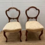 A pair of mahogany balloon back chairs, upholstered in white