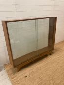 A mid- century teak display unit, glazed front and rear on splayed legs and with two shelves. Height